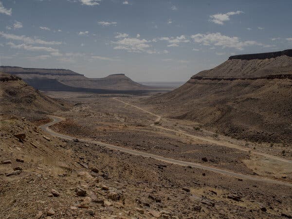 A road passes through hills in a dry valley.