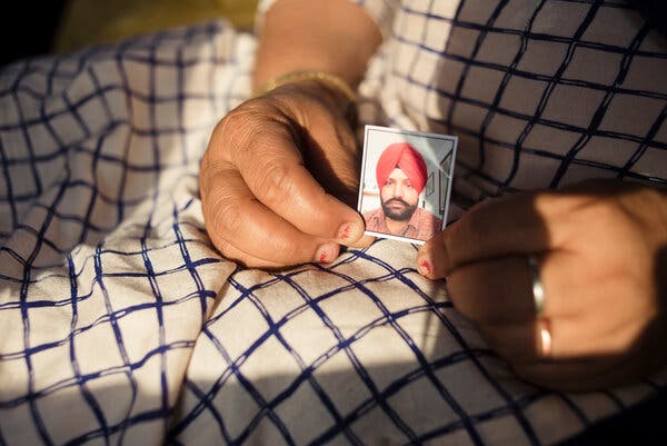 A woman holds in her lap a small picture of a man with a red turban.