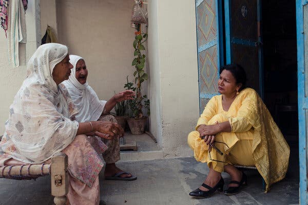 Three women talk near the door into a building. 