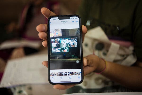 A hand holds a phone, which shows images from security cameras. 