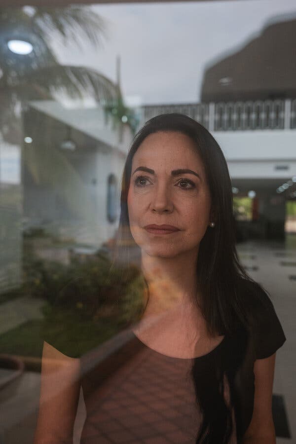 Ms. Machado wearing a dark shirt as she looks through glass.