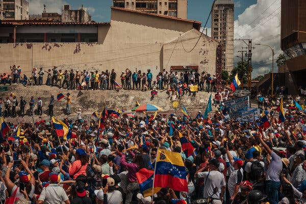 People attend a political rally. Some wave the Venezuelan flag.