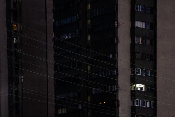 A single bright light appears to be on in an otherwise darkened apartment building. 